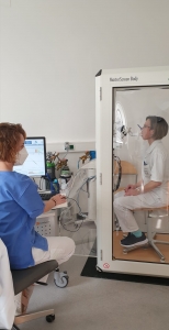 Lungenfunktionstest Szene. Eine Patientin bläst in das Gerät, eine Mitarbeiterin überwacht den Test